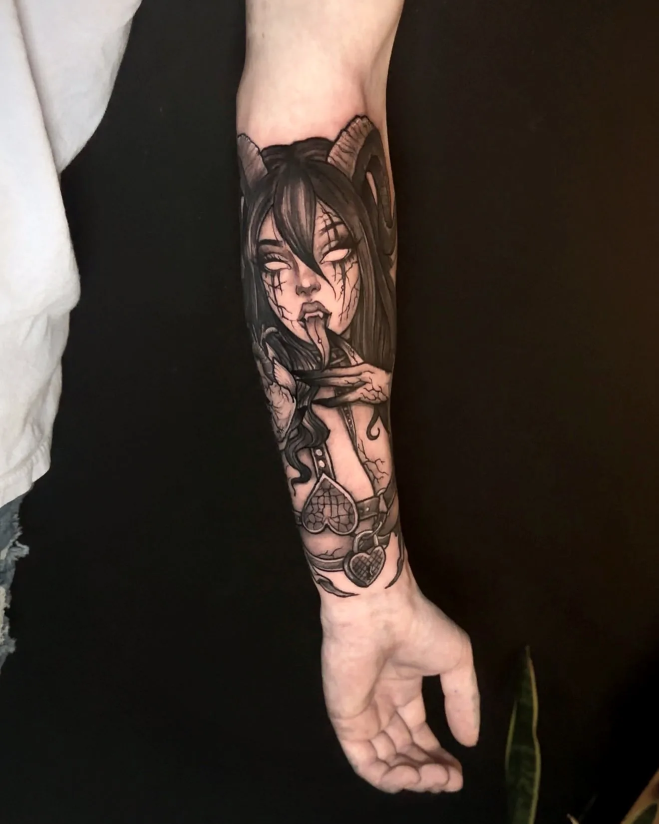 A horned woman's portrait down a forearm, her eyes closed, in fine black and grey.