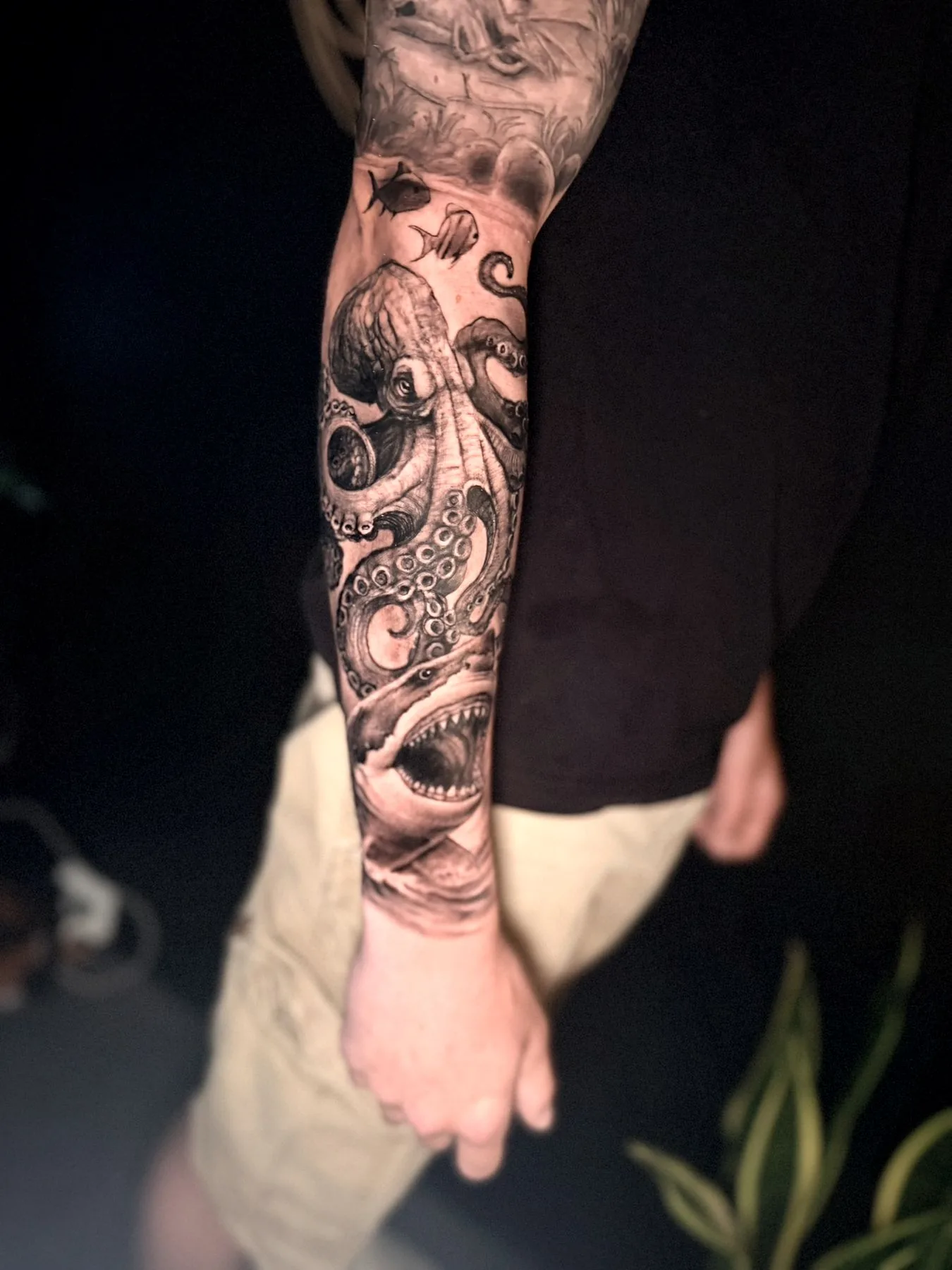 An ocean sleeve in black and grey, an octopus and a roaring face wrapping a forearm.