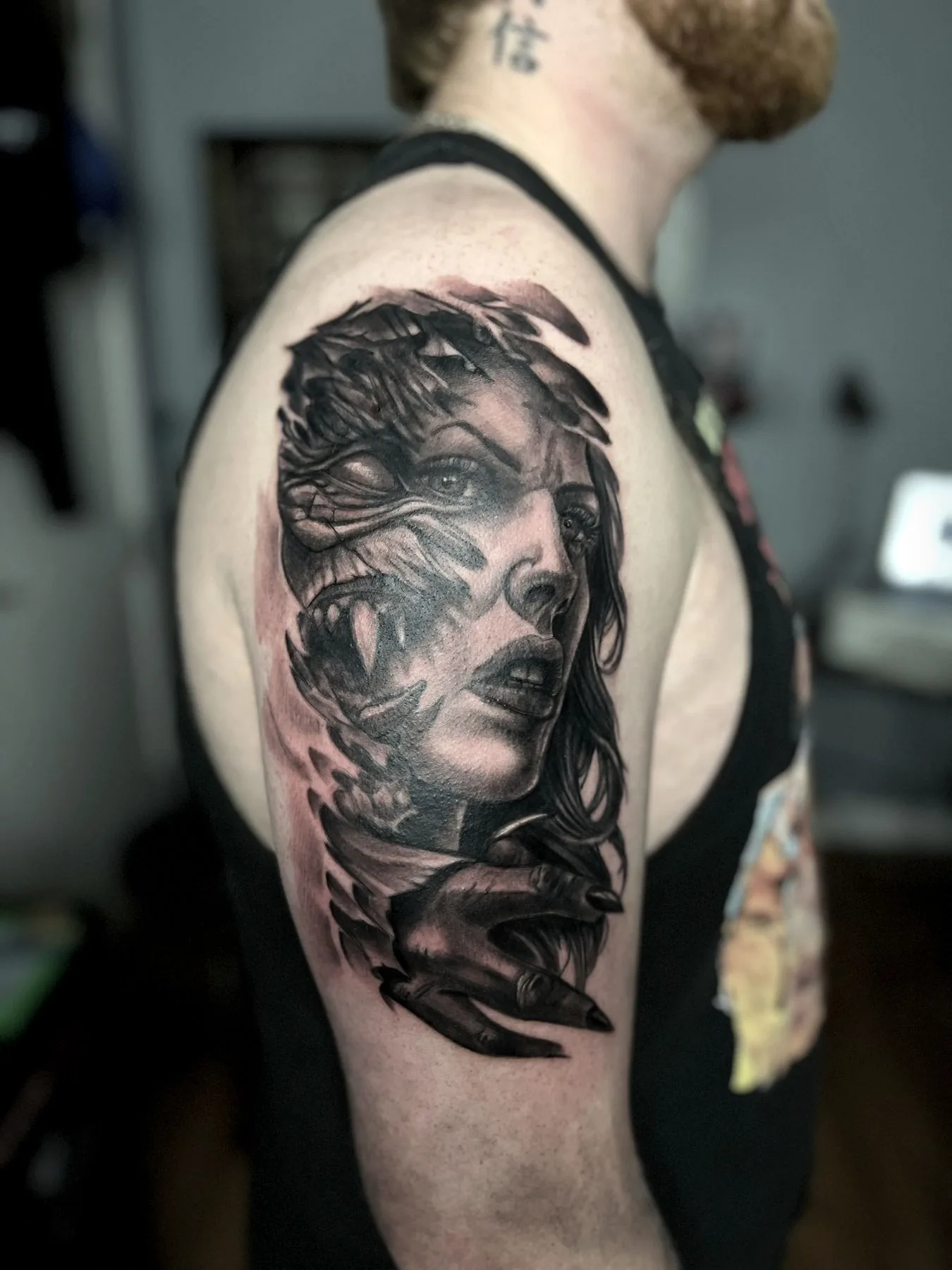 A woman with a raven, tattooed on an upper arm in black and grey realism.