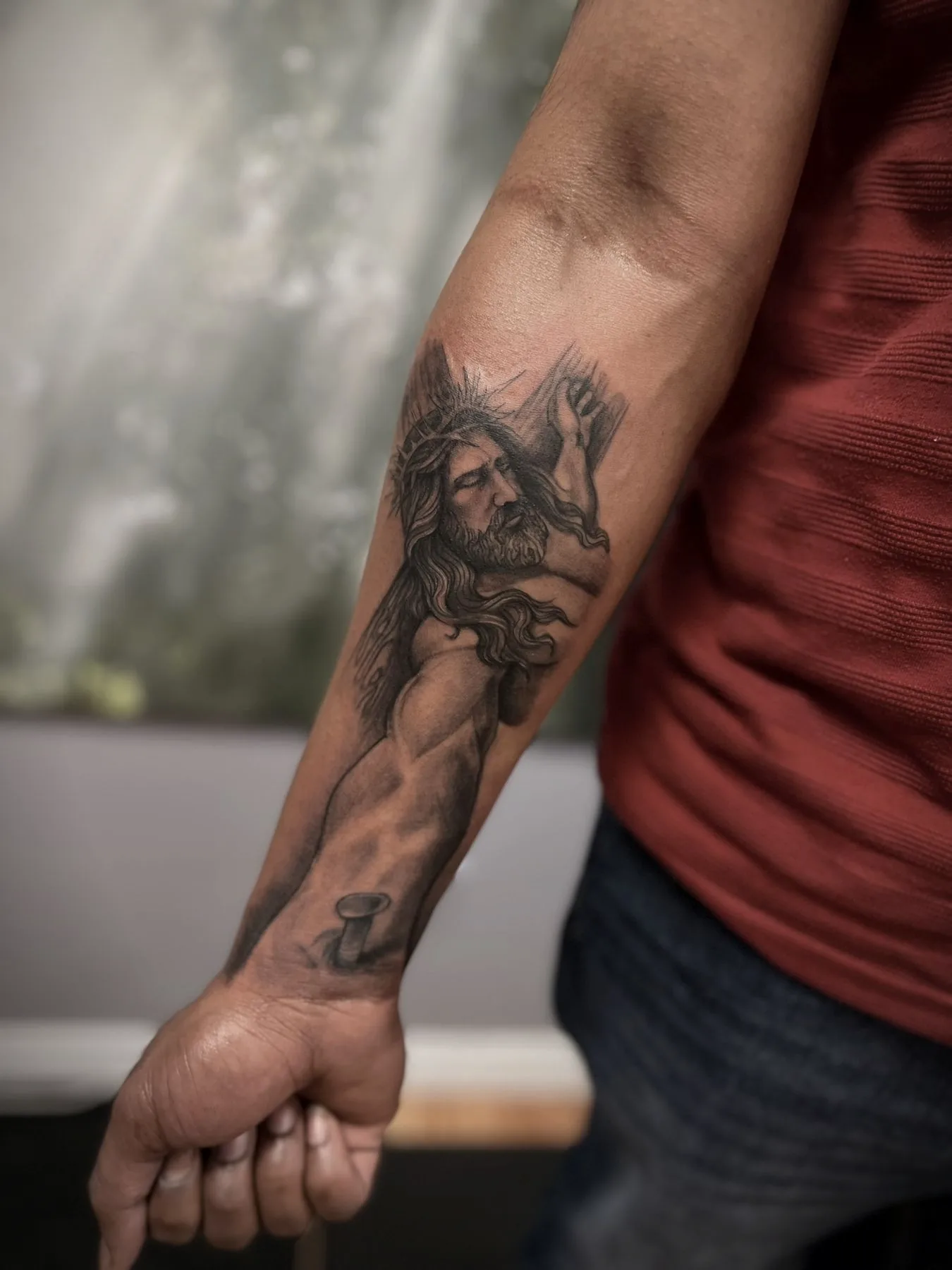 Zeus mid-stride with a thunderbolt, tattooed along a forearm in black and grey realism.