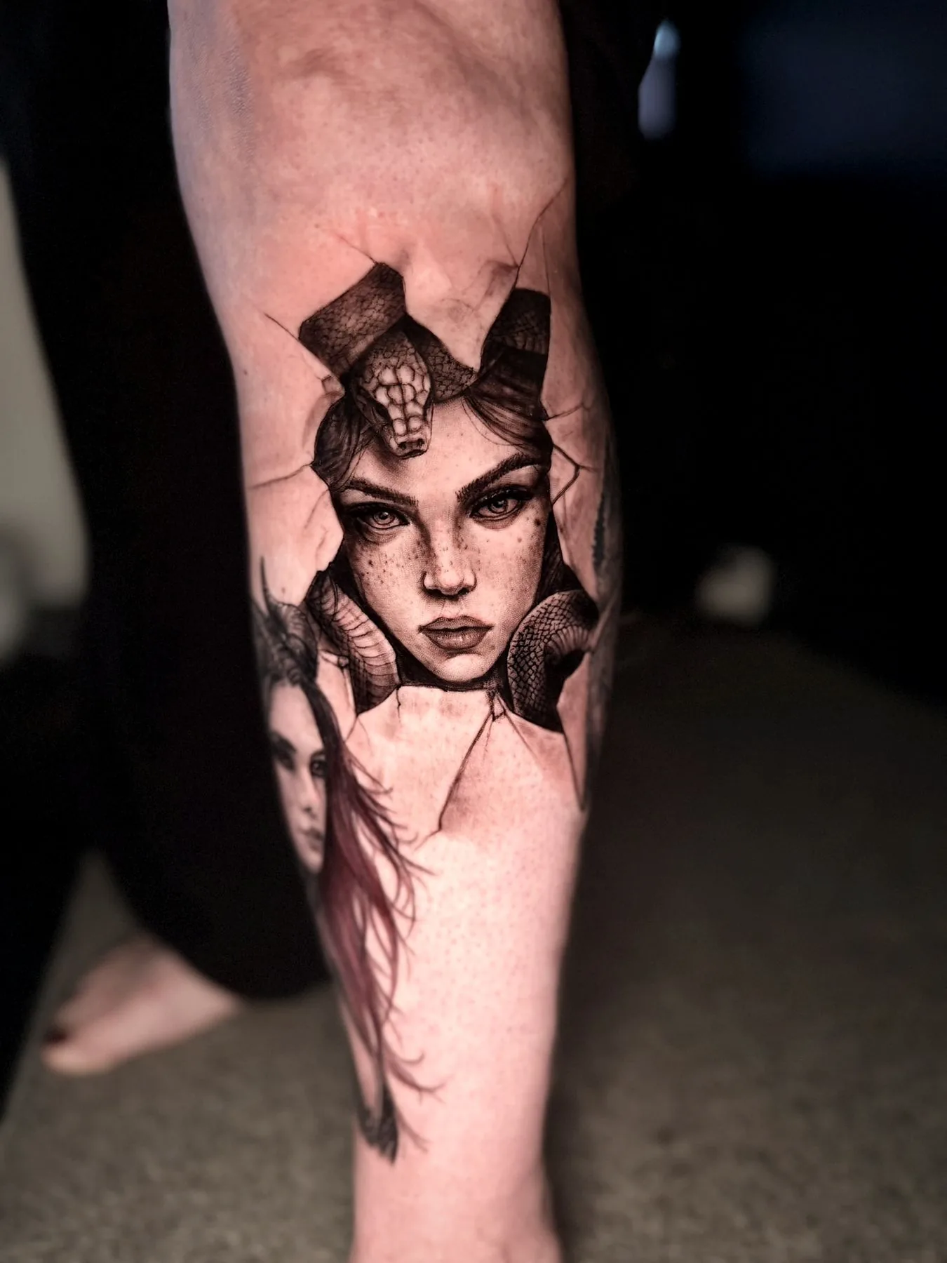 Medusa's portrait down a forearm, her hair worked in auburn red against black and grey.