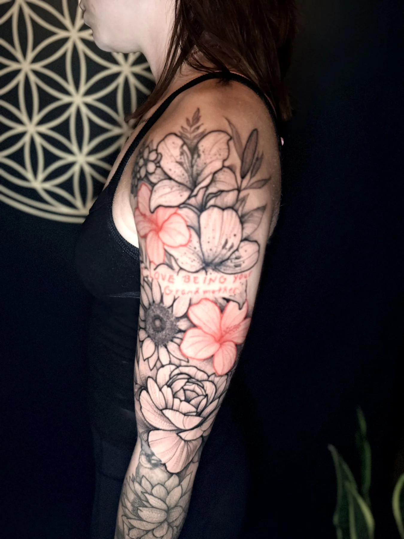 A floral sleeve in fine black and grey with red flowers, and a line of red handwriting reading 'Love being your grandmother'.