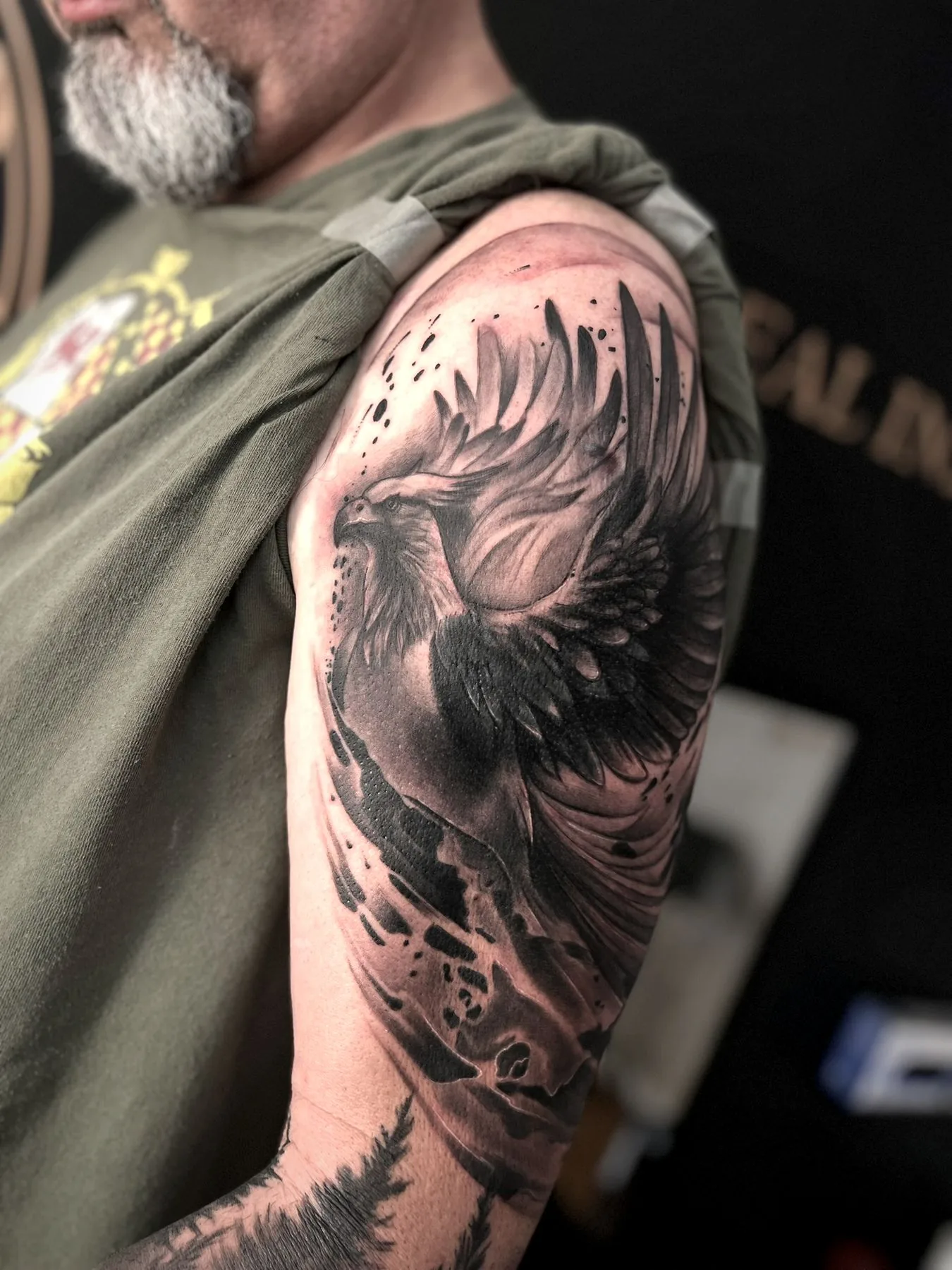 An eagle with open wings over mountains, tattooed across a shoulder and upper arm.